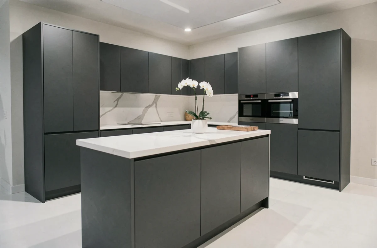 Cuisine SieMatic haut de gamme exposée dans le showroom de Versailles, avec des façades laquées graphite sans poignées et un îlot central en quartz